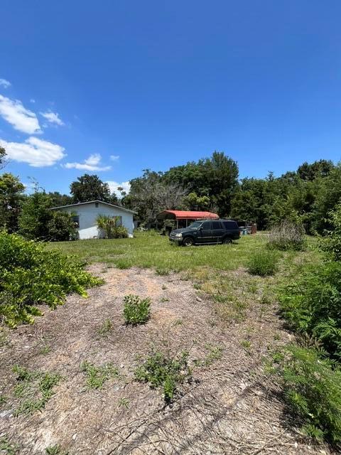 A small house with a metal carport and a dark SUV sits on a grassy lot — 727 S Washington Avenue, FL 32703, FL