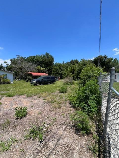 A black SUV is parked on a grassy lot next to a chain-link fence — 727 S Washington Avenue, FL 32703, FL