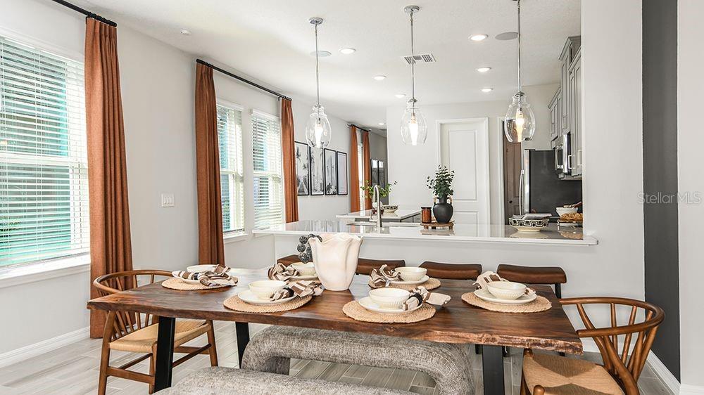 A dining area with a wooden table and bench sits in front of a kitchen island — 5795 PORTICO PLACE, KISSIMMEE, FL