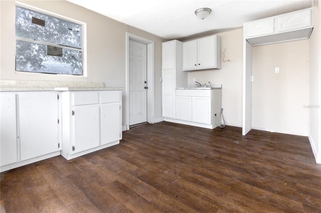 A kitchen features white cabinets, dark wood-look flooring, a window, and an exterior door — 642 PETERSON STREET, WAUCHULA, FL