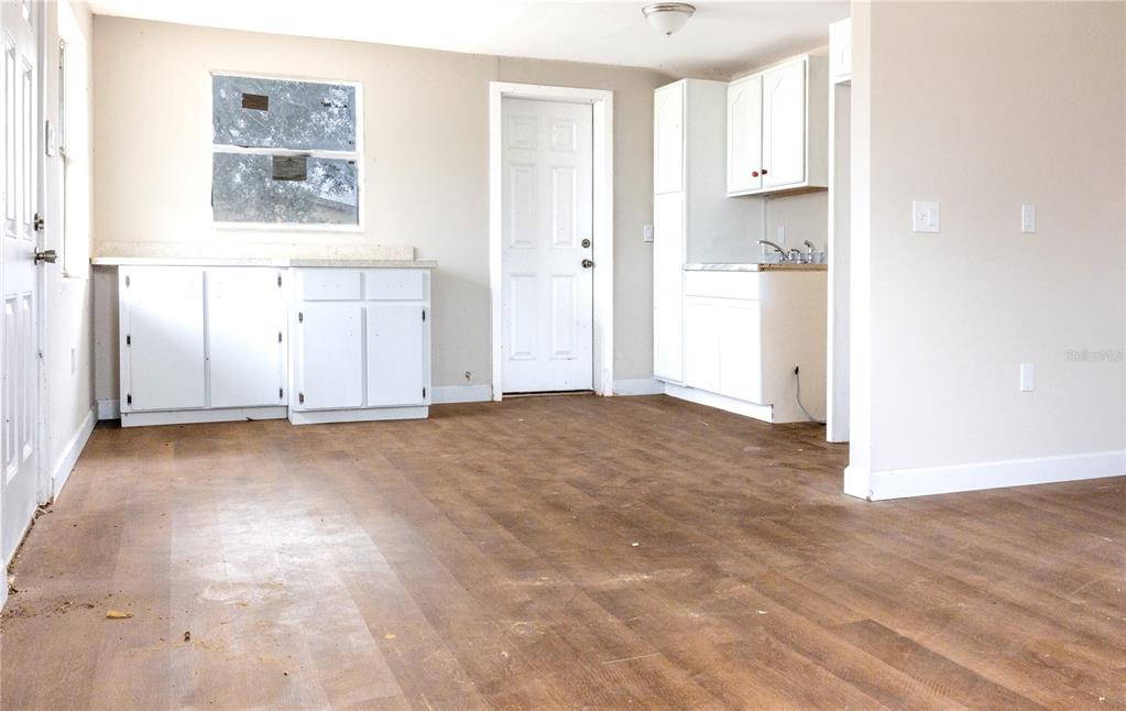 A kitchen area features white cabinets, wood-look flooring, and a window on a beige wall — 642 PETERSON STREET, WAUCHULA, FL