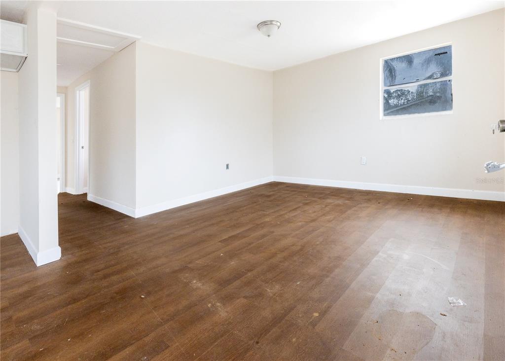 An empty room with wood-look flooring, beige walls, a single window, and a ceiling light — 642 PETERSON STREET, WAUCHULA, FL