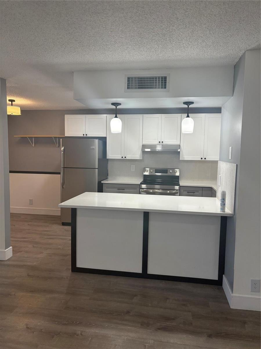 A kitchen features white upper cabinets, gray lower cabinets, stainless steel appliances, and a peninsula — 5492 Courtyard Drive # 5492, Margate FL 33063, MARGATE, FL