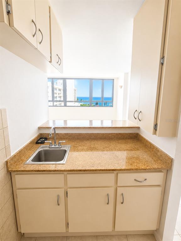 A kitchen area features light-colored cabinets, a granite countertop, a sink, and a window view — 1452 MAGDALENA AVE UNIT 9C, SAN JUAN, PR