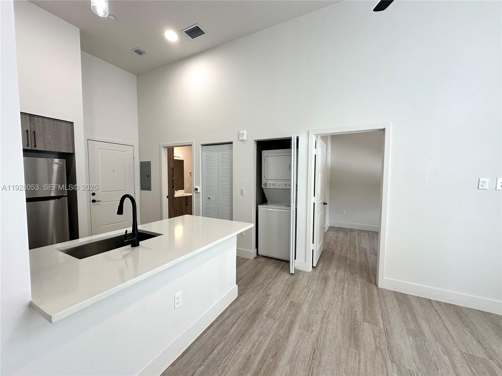 A kitchen with a white island and stainless steel appliances opens to a laundry closet — 18412 Homestead Ave # 110, Miami FL 33157, MIAMI, FL