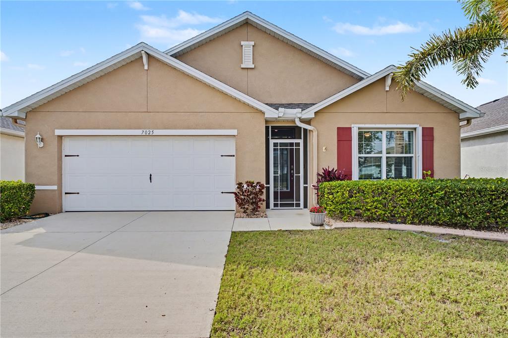 A single-story house with a beige stucco exterior, a two-car garage, and a front lawn — 7025 WATERFORD PARKWAY, PUNTA GORDA, FL