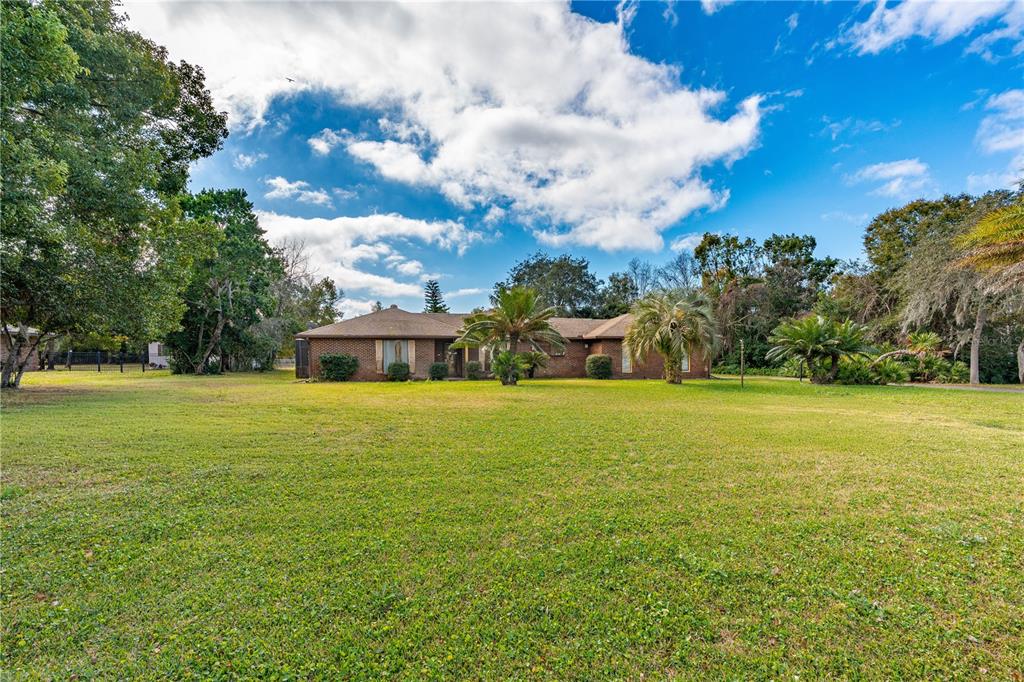 A single-story brick house sits in the center of a large, grassy lawn — 810 HENSEL HILL ROAD W, PORT ORANGE, FL
