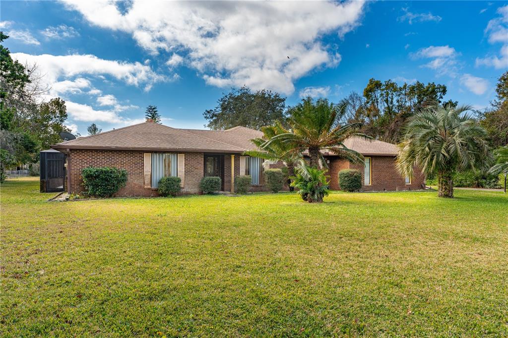 A single-story brick house with a brown shingled roof sits on a large grassy lawn — 810 HENSEL HILL ROAD W, PORT ORANGE, FL