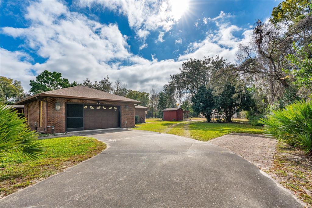 A brick house with a garage and a small red shed on a grassy lot — 810 HENSEL HILL ROAD W, PORT ORANGE, FL