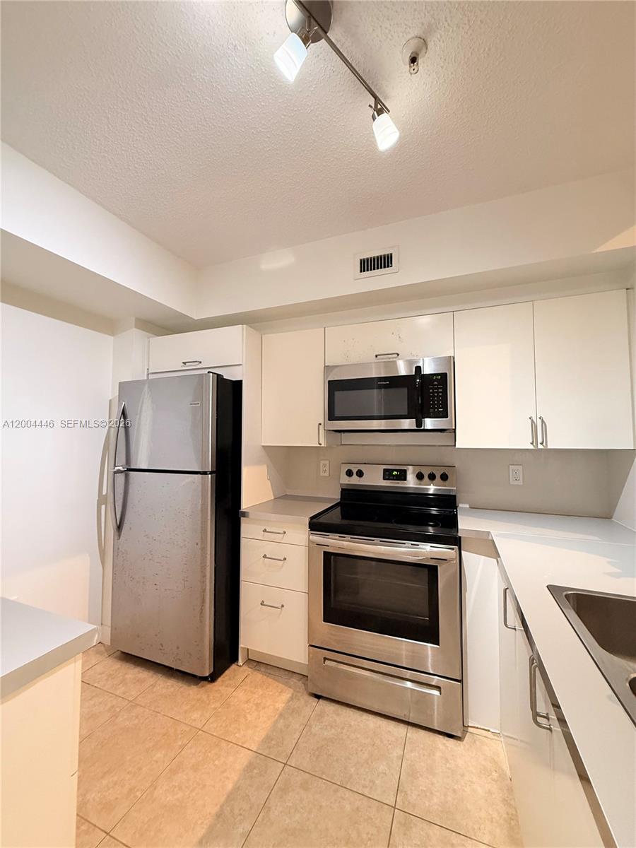 A kitchen features stainless steel appliances, white cabinets, and light-colored tile flooring — 2200 E Preserve Way # 301, Miramar FL 33025, MIRAMAR, FL