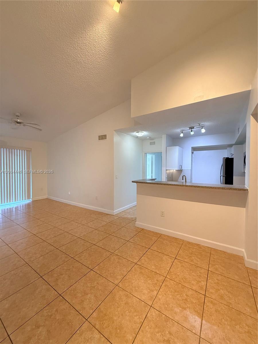 An open-concept living area features tan tile flooring, a breakfast bar, and vaulted ceilings — 2200 E Preserve Way # 301, Miramar FL 33025, MIRAMAR, FL