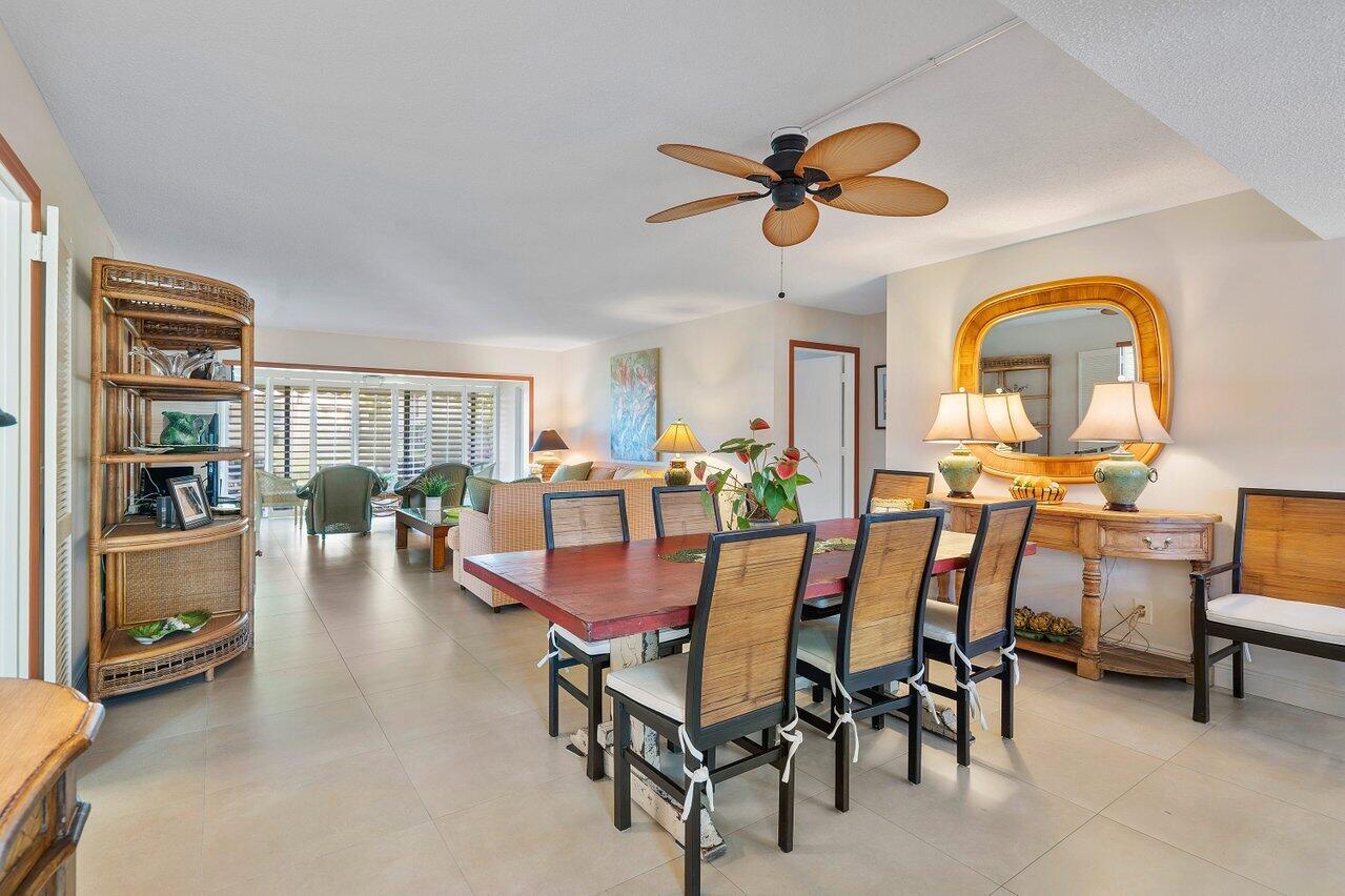 A dining area with a wooden table and chairs sits in front of a living room — 3677 Quail Ridge Drive # B, Boynton Beach FL 33436, BOYNTON BEACH, FL