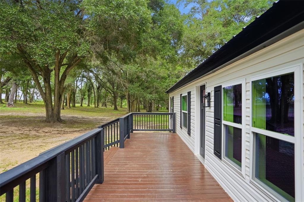 A single-story white house with a black metal roof and two front decks — 28470 SOARING HAWK LANE, BROOKSVILLE, FL