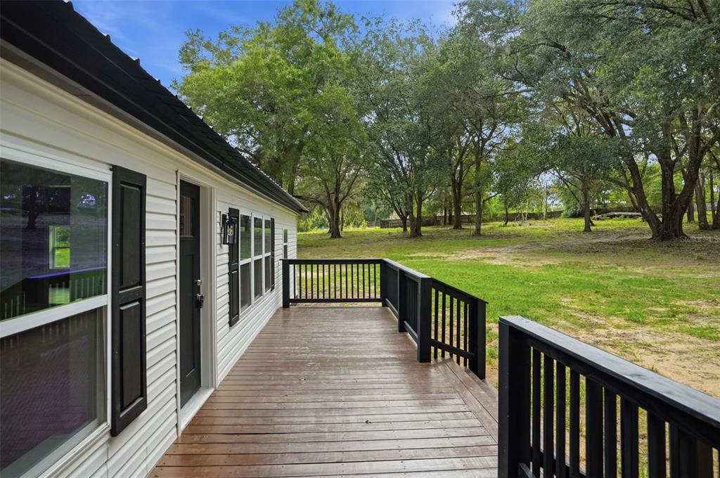 A wooden deck with black railings runs along the side of a white house — 28470 SOARING HAWK LANE, BROOKSVILLE, FL