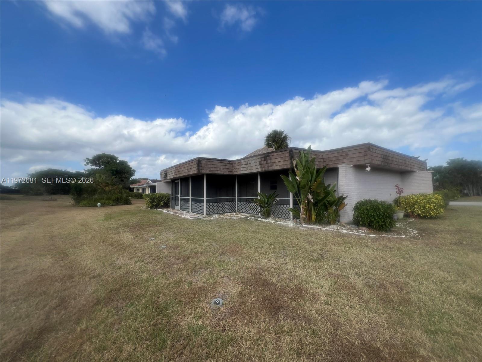A single-story house with a screened-in porch sits on a large, grassy lot — 5724 S Bayberry Ln, Tamarac FL 33319, TAMARAC, FL