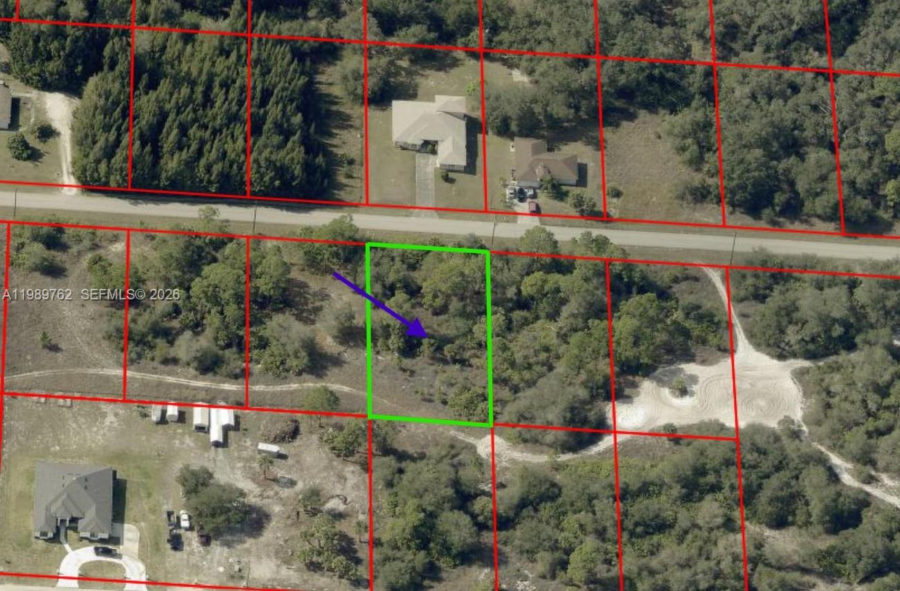 This aerial view shows a vacant, wooded residential lot outlined in green — 1812 MOORE AVE, Lehigh Acres FL 33972, LEHIGH ACRES, FL