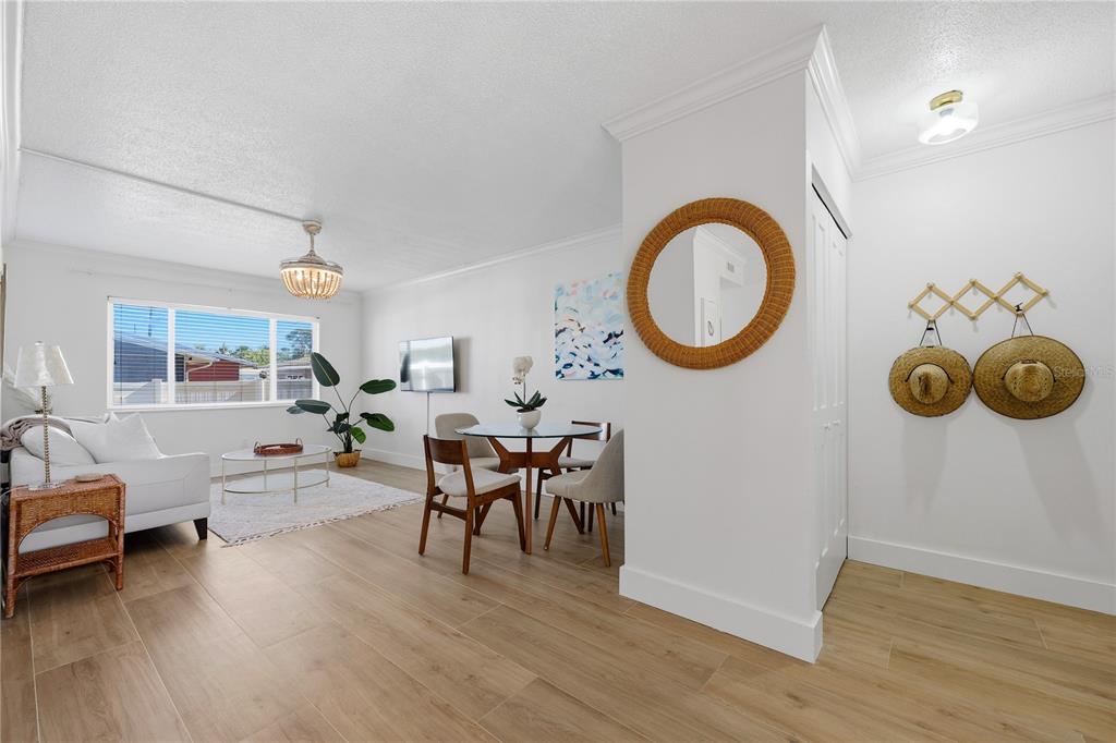 A bright living and dining area features light wood-look flooring, white walls, and modern decor — 3575 GULF BOULEVARD UNIT 105, ST PETE BEACH, FL