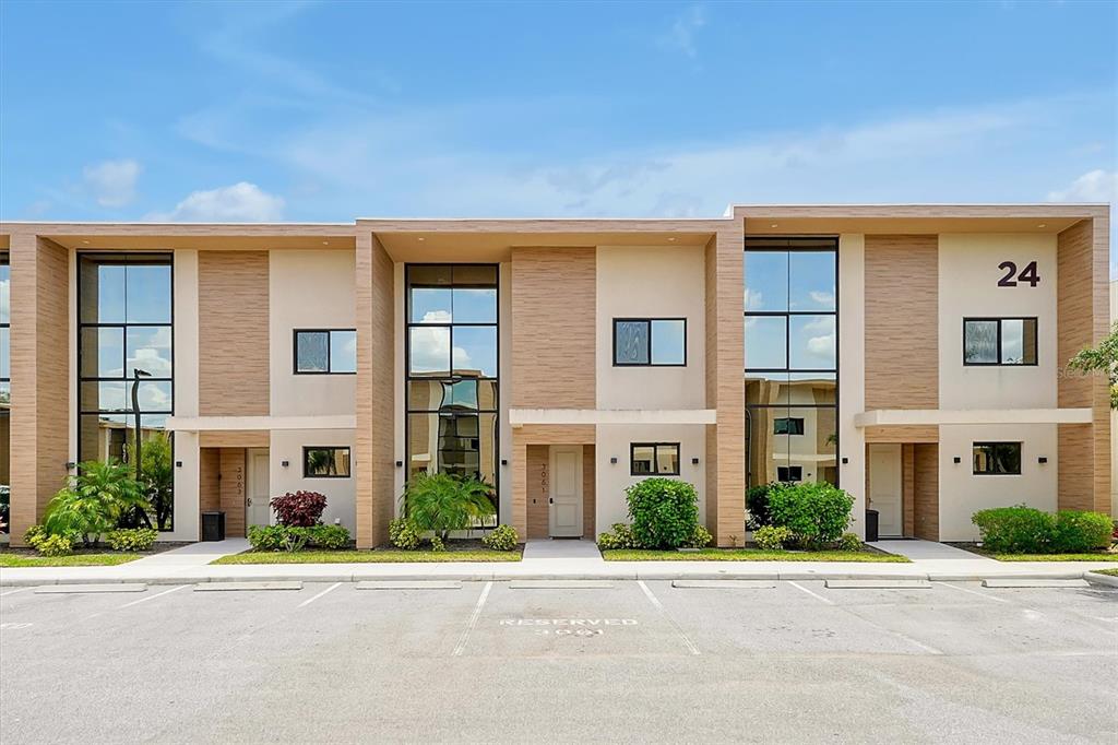 A modern multi-unit residential building with light-colored siding, large windows, and a paved parking lot — 3061 ROCKEFELLER WAY, KISSIMMEE, FL