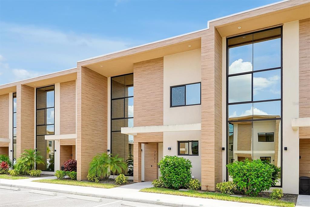 The exterior of a modern two-story townhouse features wood-look siding and large glass windows — 3061 ROCKEFELLER WAY, KISSIMMEE, FL
