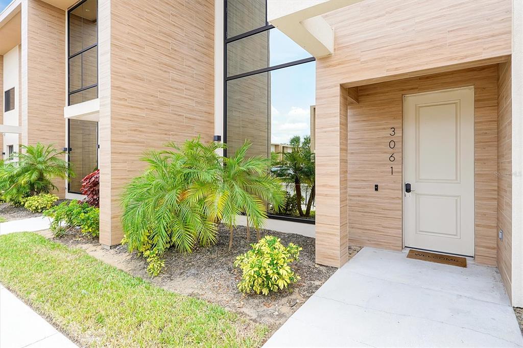 The exterior of a modern building features wood-look siding, a glass window, and a door — 3061 ROCKEFELLER WAY, KISSIMMEE, FL