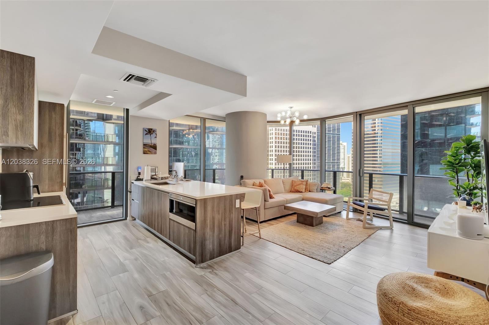 A modern open-concept apartment features a kitchen island, living area, and floor-to-ceiling windows — 801 S Miami Ave # 2205, Miami FL 33130, MIAMI, FL