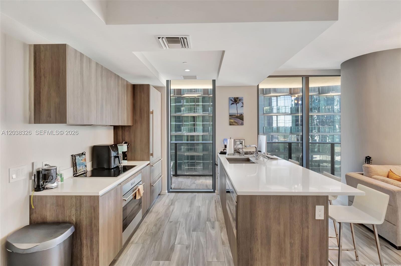 A modern kitchen features wood-toned cabinetry, white countertops, and a balcony with city views — 801 S Miami Ave # 2205, Miami FL 33130, MIAMI, FL