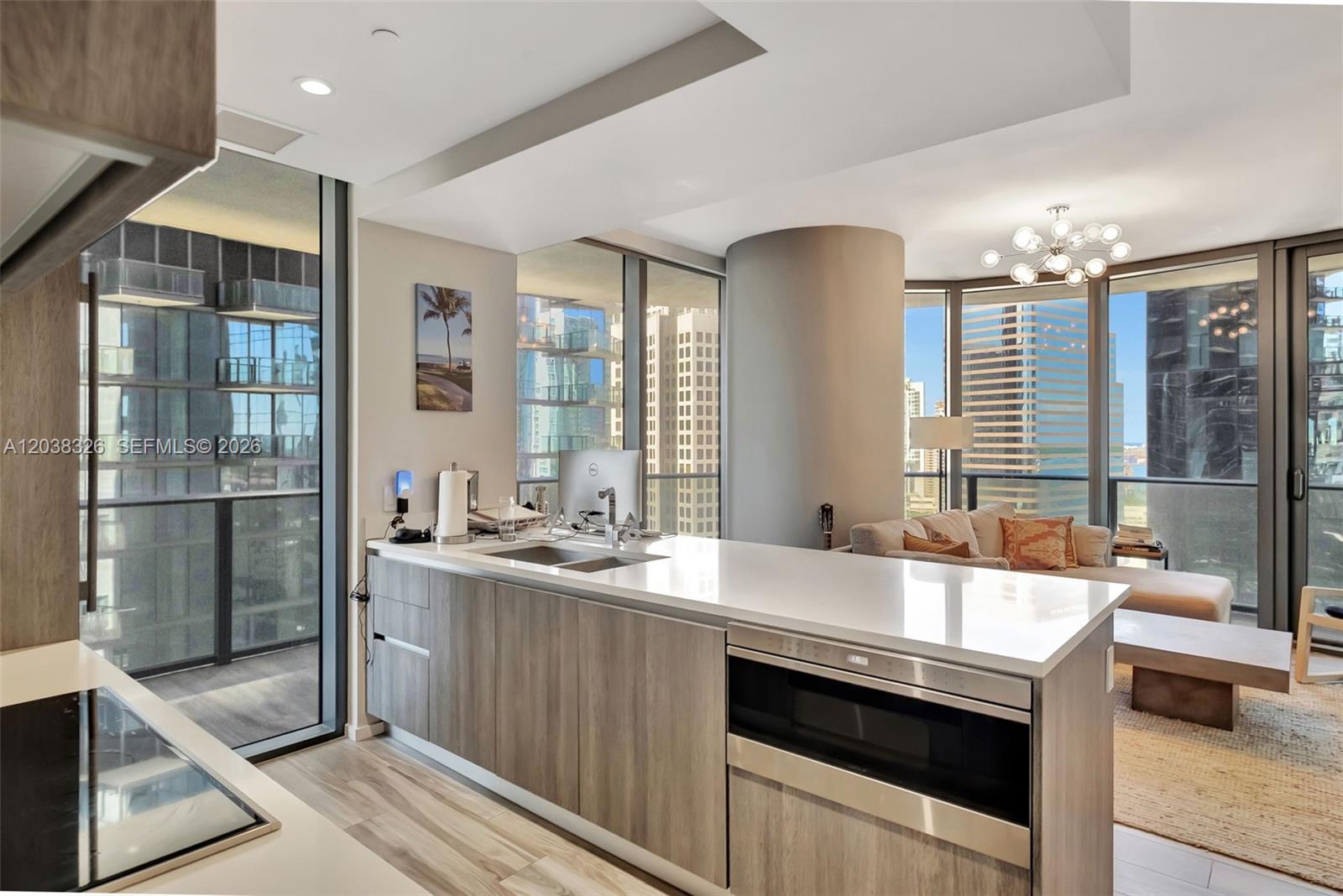 A modern kitchen island with a white countertop and wood cabinetry faces a living area — 801 S Miami Ave # 2205, Miami FL 33130, MIAMI, FL