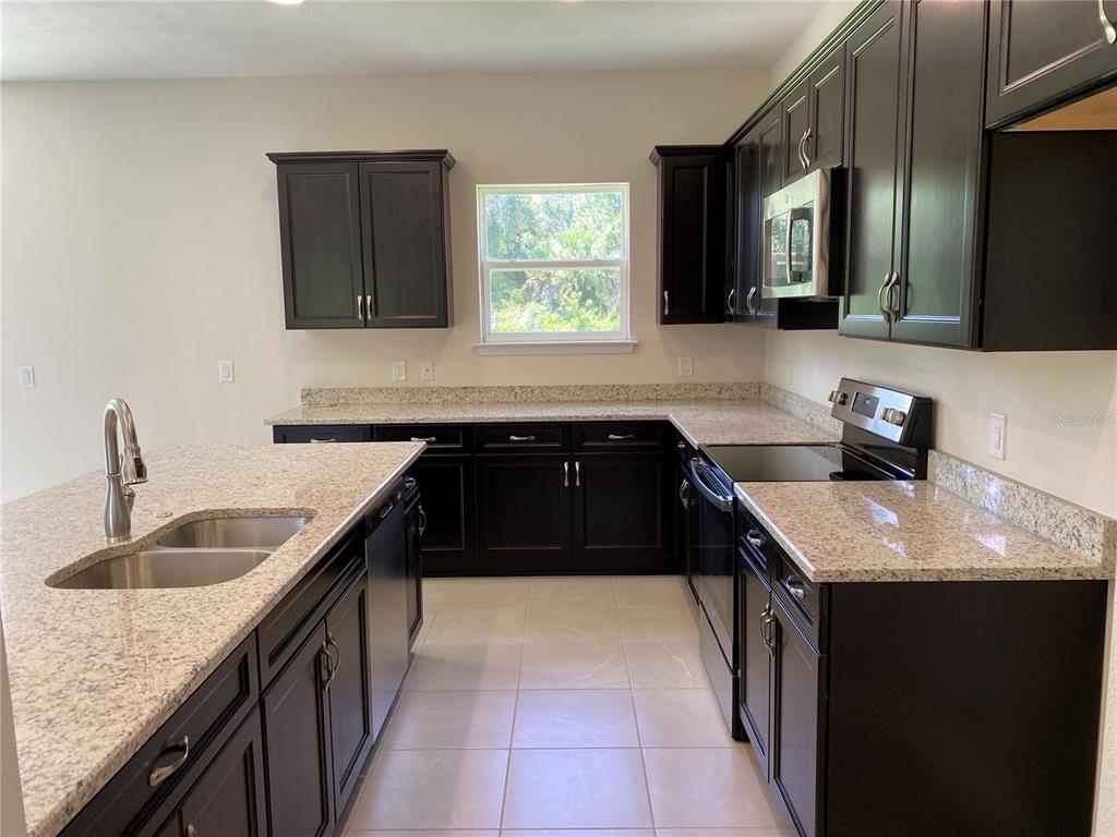A kitchen features dark wood cabinets, granite countertops, stainless steel appliances, and a center island — 3467 INVERNESS STREET, NORTH PORT, FL