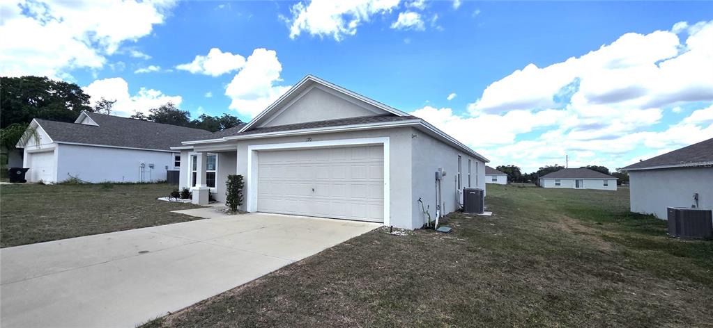A light-colored, single-story suburban house features a two-car garage and a concrete driveway — 170 W 6TH STREET, FROSTPROOF, FL