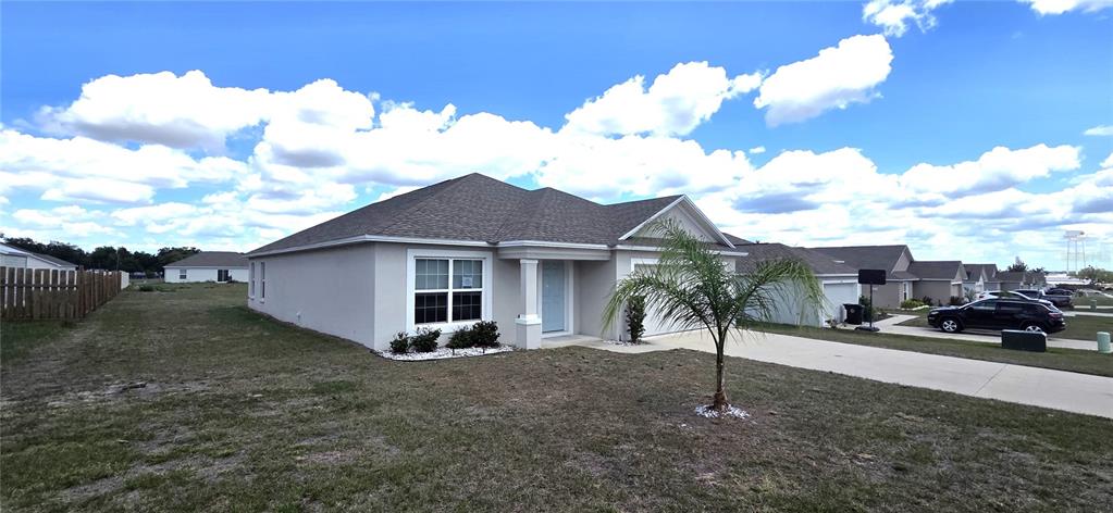 A single-story beige house with a gray shingled roof and a small palm tree — 170 W 6TH STREET, FROSTPROOF, FL