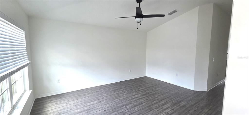 An empty room features white walls, dark wood-look flooring, and a ceiling fan — 170 W 6TH STREET, FROSTPROOF, FL