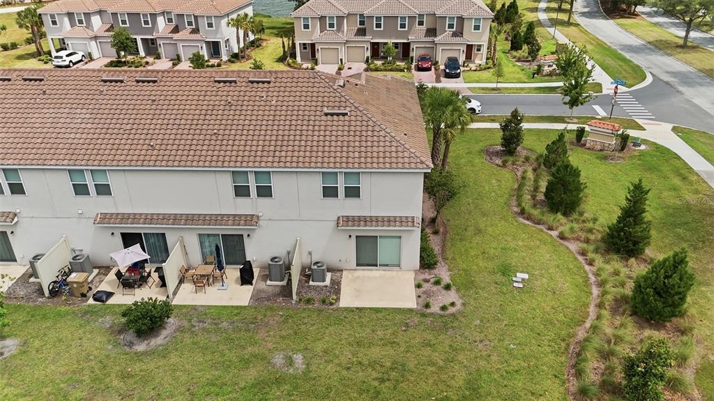 An aerial view shows the rear exterior of a multi-unit townhouse with concrete patios — 3684 CIRCLE HOOK STREET, KISSIMMEE, FL