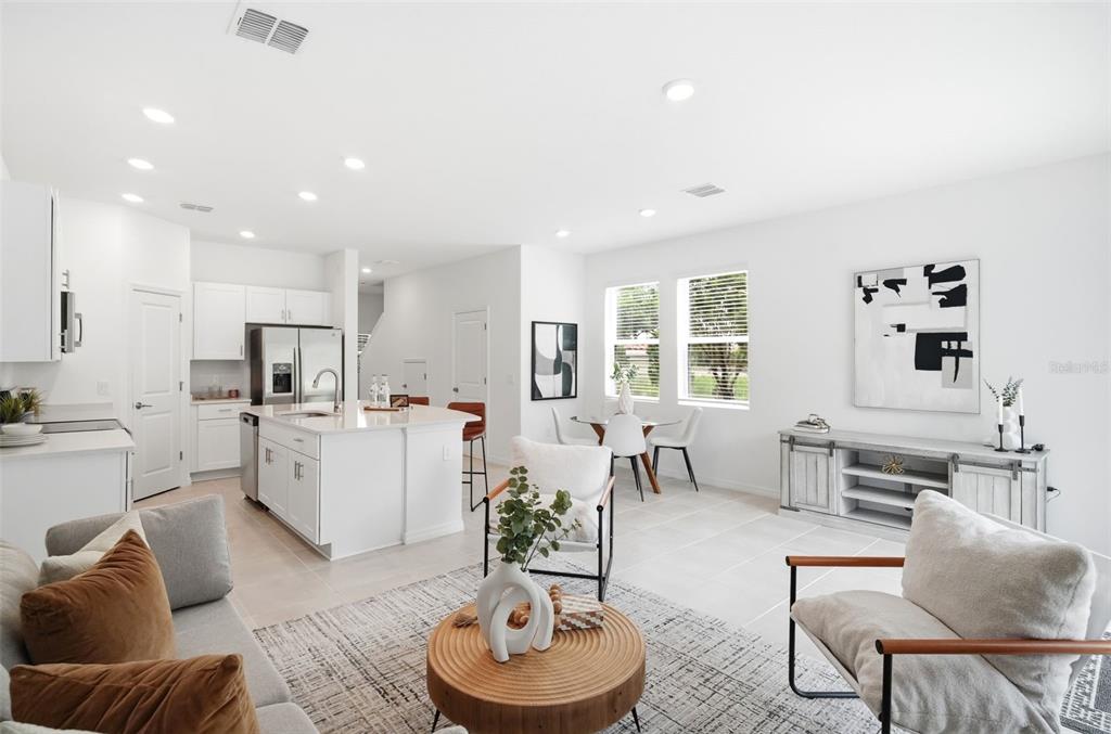 An open-concept kitchen and living area features white cabinetry, a center island, and tile flooring — 3684 CIRCLE HOOK STREET, KISSIMMEE, FL