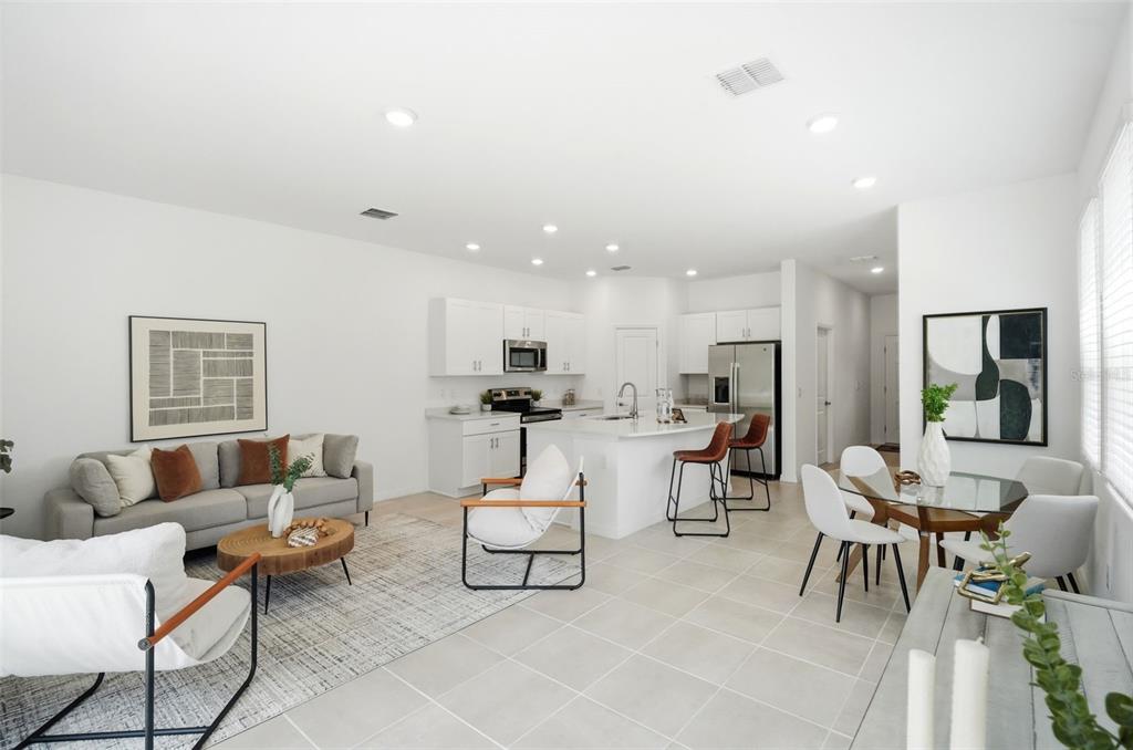 An open-concept living room and kitchen featuring white cabinetry, a central island, and tile flooring — 3684 CIRCLE HOOK STREET, KISSIMMEE, FL