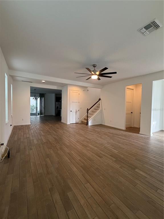 An open living area features wood-look tile flooring, a ceiling fan, and a staircase — 8210 NEMOURS PARKWAY, ORLANDO, FL
