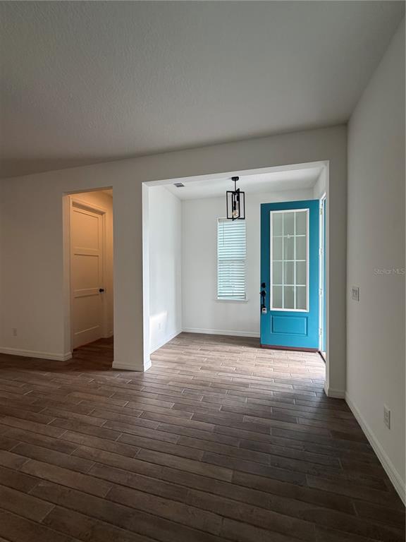 An entryway with wood-look tile flooring, a teal front door, and a modern pendant light — 8210 NEMOURS PARKWAY, ORLANDO, FL
