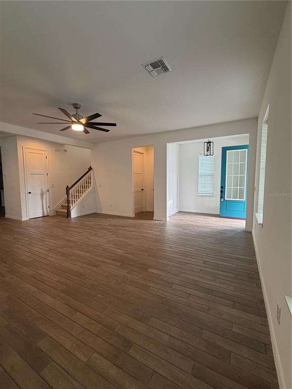 An open living area features wood-look tile flooring, a ceiling fan, and a blue front door — 8210 NEMOURS PARKWAY, ORLANDO, FL