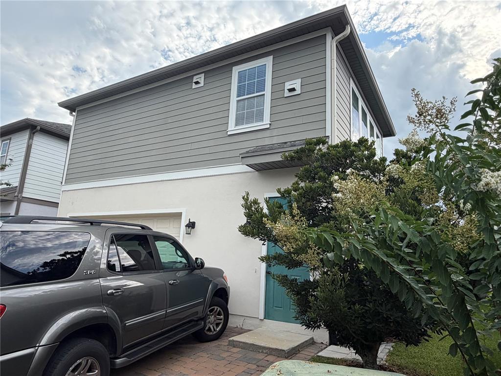 A two-story house exterior features gray horizontal siding, a stucco lower level, and a teal door — 8210 NEMOURS PARKWAY, ORLANDO, FL