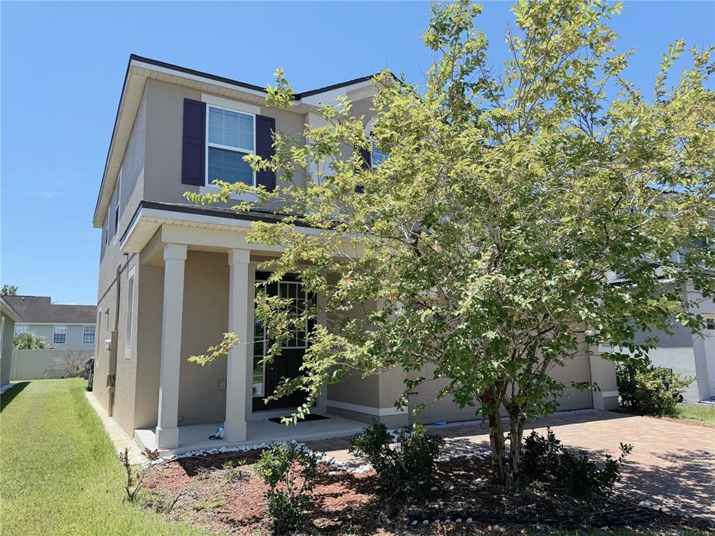 A two-story house with a tan exterior, a front porch with columns, and a paved driveway — 2428 CHATEAU LOOP, KISSIMMEE, FL