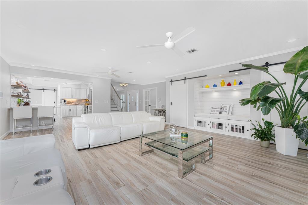 A bright living room features white leather sofas, a glass coffee table, and wood-look flooring — 139 SEVILLE PLACE SW, PORT CHARLOTTE, FL
