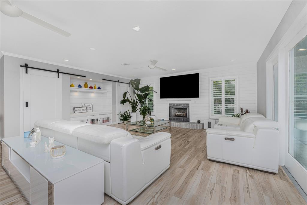 A bright living room features white leather sofas, a fireplace, and light wood-look flooring — 139 SEVILLE PLACE SW, PORT CHARLOTTE, FL
