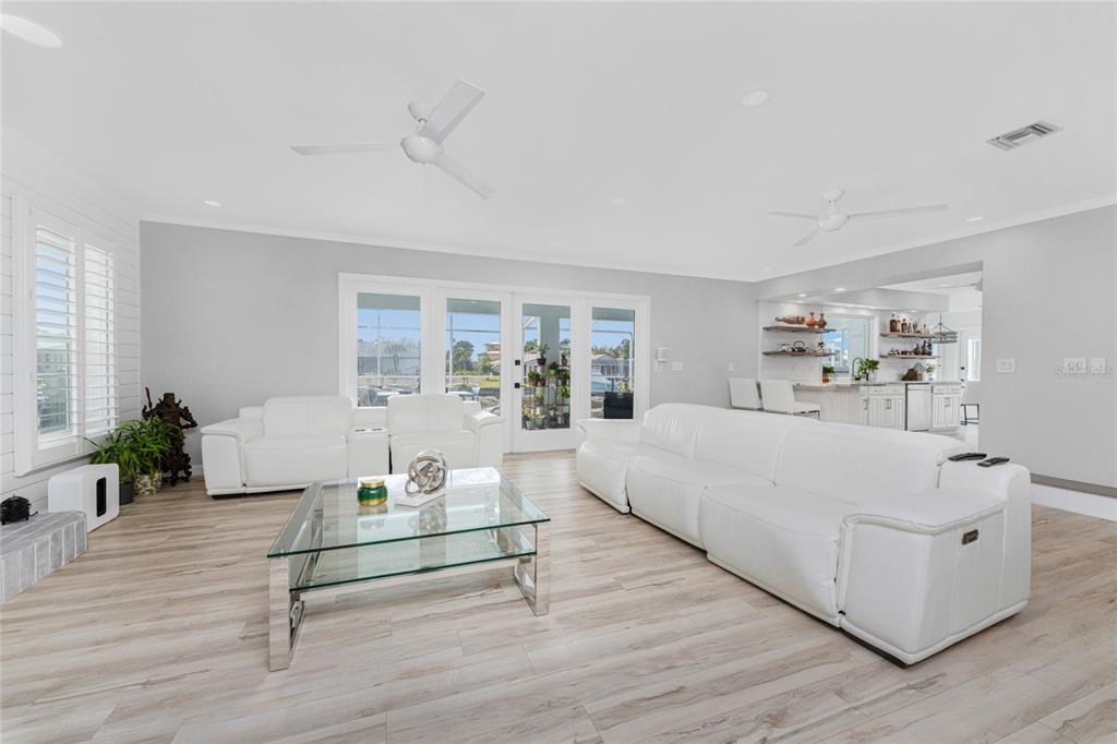 A bright living room features white leather sofas, a glass coffee table, and wood flooring — 139 SEVILLE PLACE SW, PORT CHARLOTTE, FL