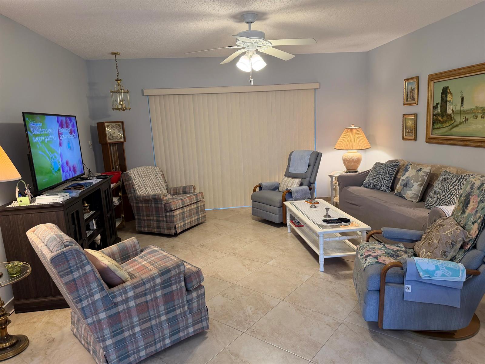 A living room features tile flooring, a ceiling fan, a television, and multiple seating areas — 701 Lori Drive # 204, Palm Springs FL 33461, PALM SPRINGS, FL