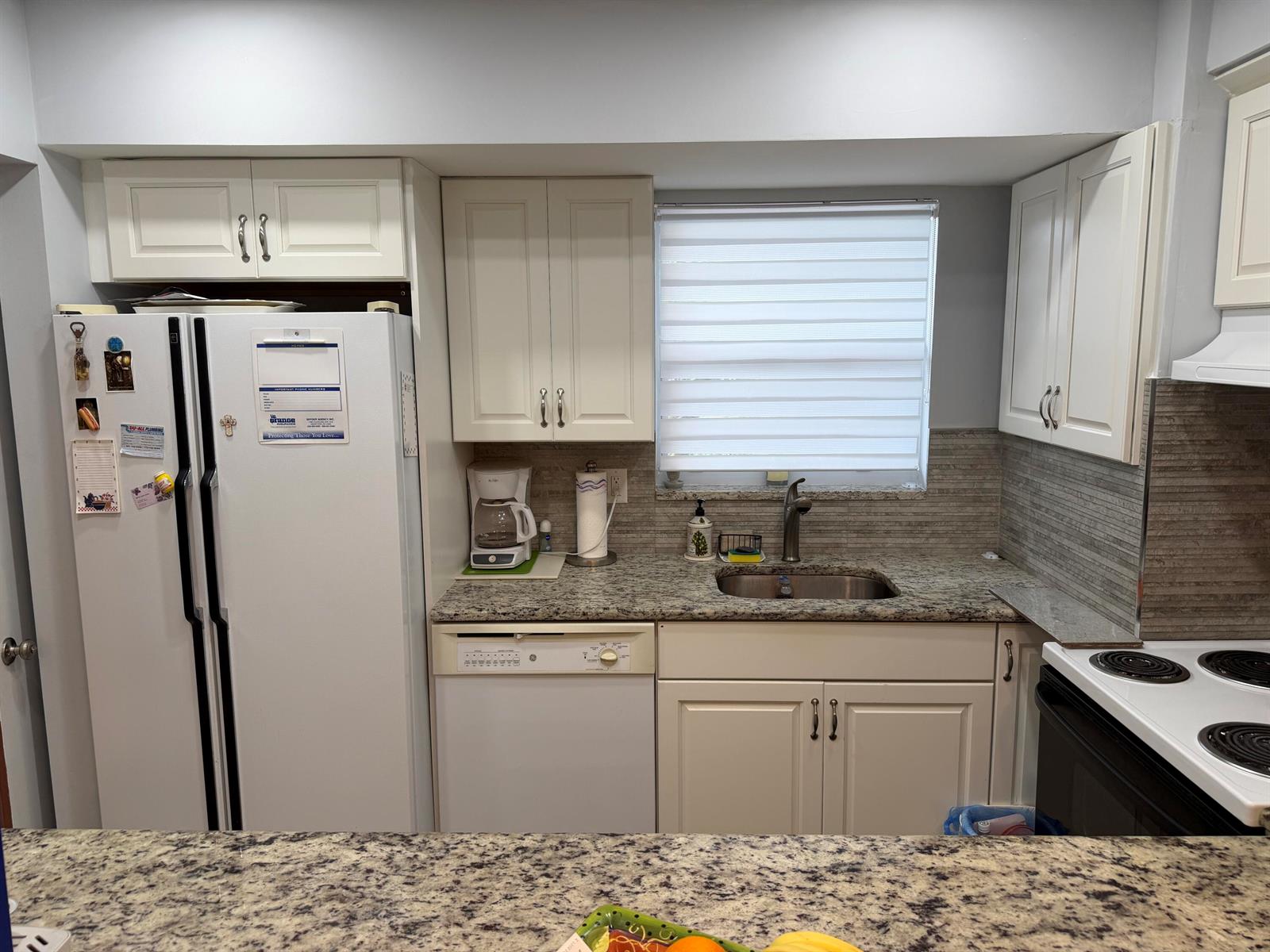 A kitchen features white cabinets, granite countertops, a stainless steel sink, and white appliances — 701 Lori Drive # 204, Palm Springs FL 33461, PALM SPRINGS, FL
