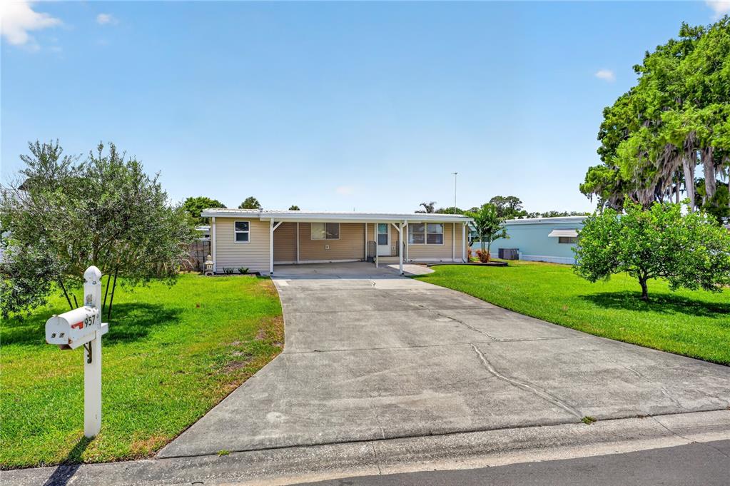 A single-story manufactured home with a concrete driveway and a white mailbox in the yard — 957 TODD WAY, TAVARES, FL