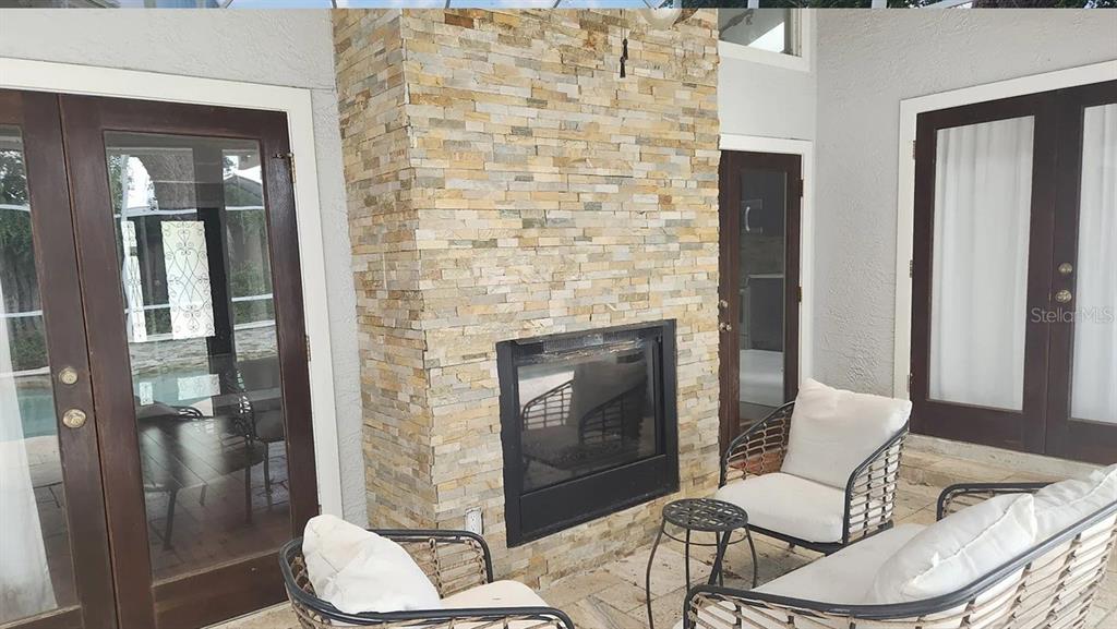 A stone-faced fireplace sits between two sets of glass doors on a covered patio — 4303 INWOOD LANDING DRIVE, ORLANDO, FL