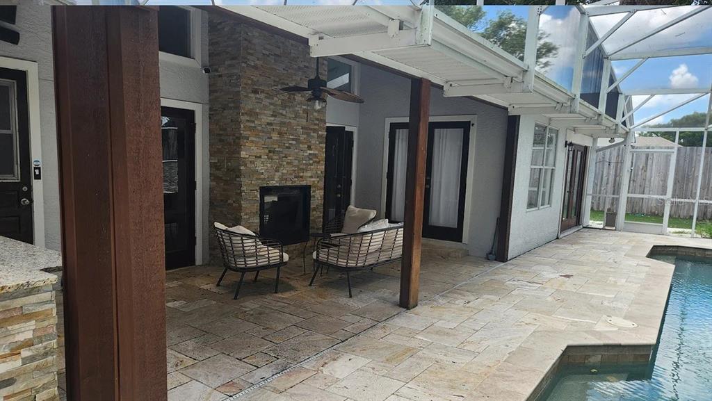 A covered patio features a stone fireplace, outdoor seating, and a pool with a screen enclosure — 4303 INWOOD LANDING DRIVE, ORLANDO, FL