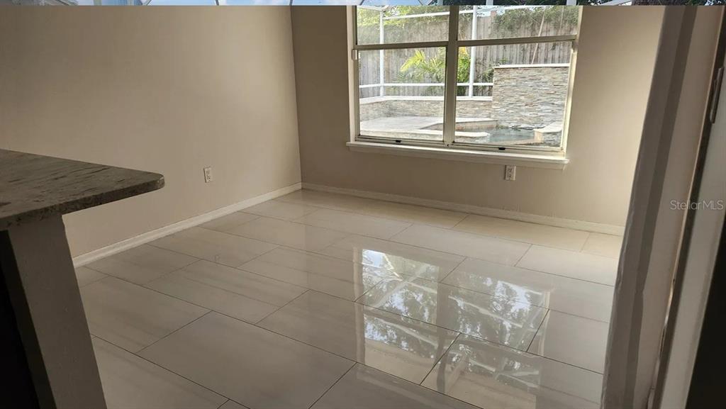 A dining area with light-colored tile flooring and a window overlooking a pool enclosure — 4303 INWOOD LANDING DRIVE, ORLANDO, FL