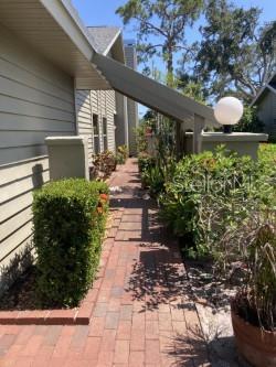 A brick walkway leads along the side of a house toward a spherical outdoor light — 3407 AVENIDA MADERA UNIT A, BRADENTON, FL