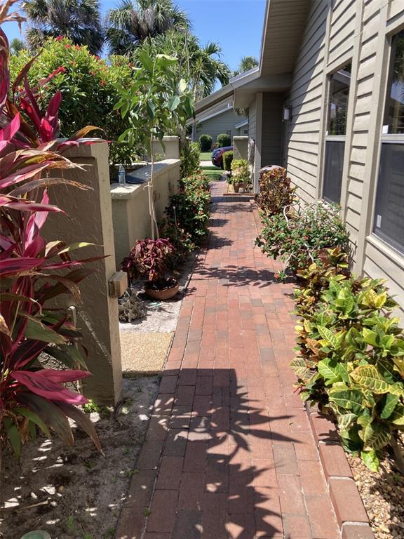 A brick walkway leads along the side of a house past various potted plants and shrubs — 3407 AVENIDA MADERA UNIT A, BRADENTON, FL
